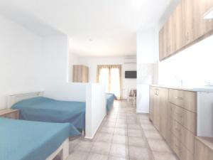 1 dormitorio blanco con 1 cama azul y cocina en Flower Apartments, en Gouves