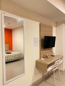 a bedroom with a mirror and a desk with a television at LagoonRoom911 in Pulosirih