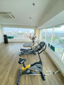 um ginásio com duas bicicletas de exercício numa sala com janelas em sewa apartment Lagoon BY Room911 em Pulosirih
