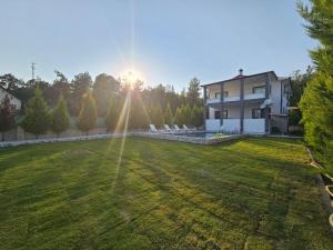 a house with a large yard with the sun shining at Fethiye Merkez Villa in Karagedik
