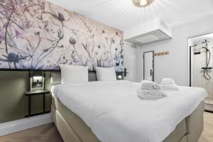 a bedroom with a large white bed and a floral wall at Dutch Design Hotel Vondelpark in Amsterdam