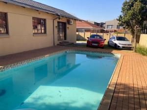 a swimming pool in front of a house with two cars at Edenvale corner in Edenvale