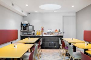 a restaurant with yellow tables and chairs and a kitchen at Dutch Design Hotel Vondelpark in Amsterdam