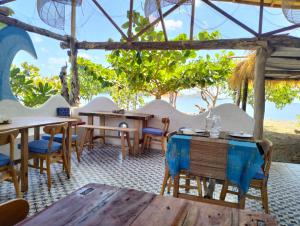 - un restaurant avec des tables et des chaises et une vue sur l'océan dans l'établissement SHAYA cottage, à Sekotong