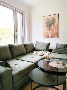 ein Wohnzimmer mit einem Sofa und 2 Tischen in der Unterkunft Apartament premium Green Dune w Porto Łeba in Łeba