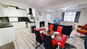 cocina y sala de estar con mesa roja y sillas en Saint Johns 3-bedroom House-Greater London, en Dartford