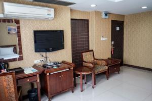 a room with a desk and a chair and a television at Grand Lucky Hotel in Bangkok