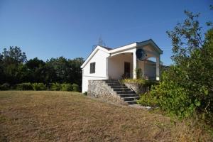 莫斯塔尔Villa Goranci的一座白色的小房子,在田野上设有楼梯