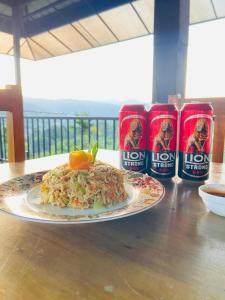 a plate of food on a table with two cans of loni at Springvalley Holiday Home in Badulla