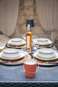 a table with plates and wine glasses and a bottle at Coquette maison & extérieur in Cognac