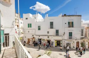a group of people walking in front of a white building at Ostuni 10min dal Mare - Dimora Luxury con Terrazza in Ostuni