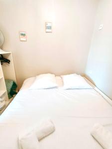 - un lit blanc dans une chambre avec 2 oreillers dans l'établissement Heol * plage à 100m*, à Larmor-Plage