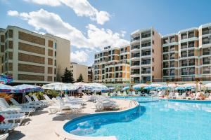 een zwembad met stoelen en parasols in een resort bij Hotel Delfin - All Inclusive in Sunny Beach