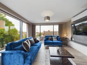 uma sala de estar com sofás azuis e uma televisão em Adelaide Apartment on Lisburn Road by Lesley em Belfast