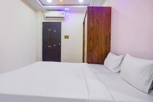 Un dormitorio con una gran cama blanca y una puerta en FabHotel Classic Square en Pune