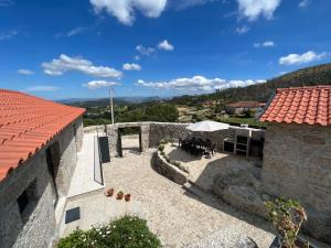 a building with a patio with a table and an umbrella at Villa Seara - Casas da Vinha in Celorico de Basto