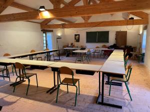Auberge de Jeunesse HI Cadouin في Le Buisson de Cadouin: غرفة كبيرة فيها طاولات وكراسي ودروس
