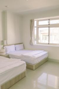 two beds in a white room with a window at TETE Homestay in Xiaoliuqiu