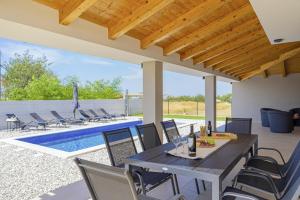 un patio con tavolo e sedie accanto alla piscina di Villa Zani in Loborika - Haus für 6-7 Personen a Loborika