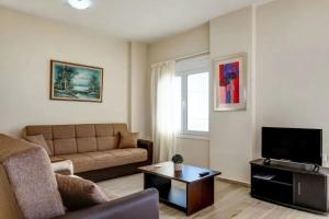 a living room with a couch and a tv at Kleio Studios in Ravdhoúkha