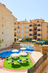 una piscina con ombrelloni, sedie e edifici di Sol y Mar Apartments a Cala Bona