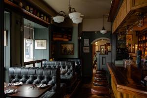 a restaurant with a bar with leather chairs and a table at The Bianconi Inn in Killorglin