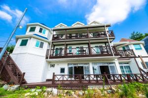 a large white house with a large balcony at Leve de Mongdol Pension in Geoje 