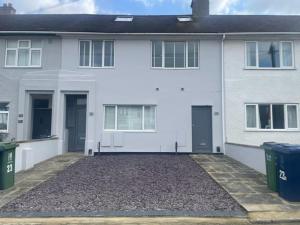 a white house with two doors and two trash cans at 23A Wharton Road in Oxford