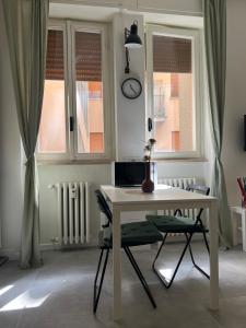 VIOLETTA DI PARMA في بارما: طاولة بيضاء وكراسي في غرفة بها نوافذ
