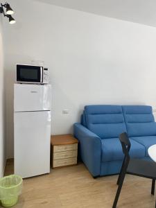un divano blu e un forno a microonde sopra un frigorifero di Medusa Apartment a Tropea