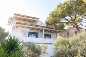 una casa bianca con degli alberi di fronte di Villa B. Calaliberotto a Cala Liberotto