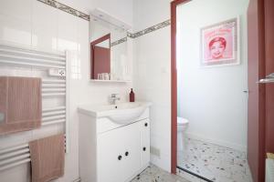 La salle de bains blanche est pourvue d'un lavabo et de toilettes. dans l'établissement LE CLOS VERSAILLES BEYNAC, à Beynac-et-Cazenac