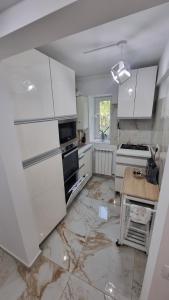 - une cuisine avec des placards blancs et un sol en marbre dans l'établissement SeaNest Mangalia, à Mangalia