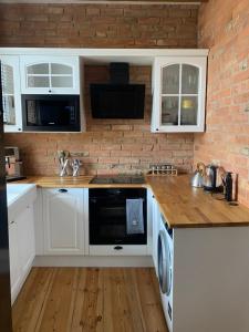 a kitchen with white cabinets and a brick wall at Apartments PSD - Wojska Polskiego 6 in Słupsk