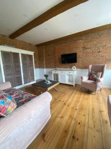 a living room with a couch and a tv and a brick wall at Apartments PSD - Wojska Polskiego 6 in Słupsk +6 photos