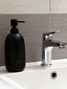 a black soap dispenser sitting on a bathroom sink at Studio Apartman Lucija in Osijek