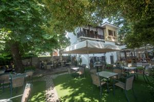 un patio al aire libre con mesas, sillas y una sombrilla en Hermes Hotel, en Khorevtón