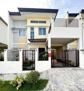 a white house with a gate in front of it at 2 Storey House 4 BR Diamond Heights Near Airport in Davao City
