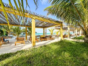 un patio con mesas y sillas de madera y el océano en Jambo Beach Hotel Paje, en Paje