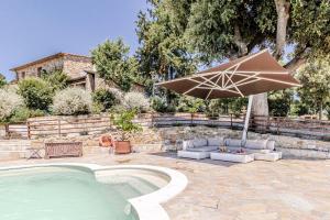 a patio with a pool and an umbrella and chairs at Villa Cedri in Montecatini Val di Cecina