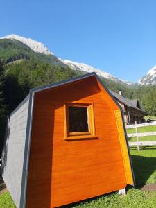 une petite maison avec une fenêtre dans l'herbe dans l'établissement Camping & Glamping Grintovec, à Preddvor