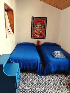 a room with two beds and a painting on the wall at Acoran Family Ocean View Guest House With Daily Yoga Practice Included North Gran Canaria PRIVATE ROOM PET FRIENDLY in Firgas