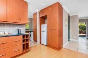- une cuisine avec des placards en bois et un réfrigérateur blanc dans l'établissement Coney Glen Penthouse, à Knysna