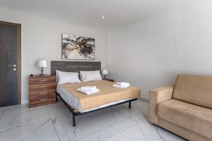 a bedroom with a bed next to a couch at Studio Penthouse 51 with side sea views at the OLO Living guesthouse in Paceville
