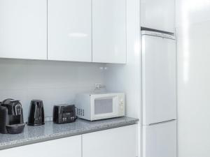 a kitchen with white cabinets and a microwave at Figueira Casino Center Apartment in Figueira da Foz