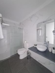 a white bathroom with a toilet and a sink at Apartamento en Playa San Marcos in Icod de los Vinos