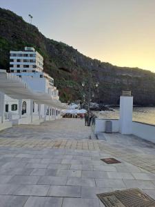 a building on the beach with people walking on it at Apartamento en Playa San Marcos in Icod de los Vinos