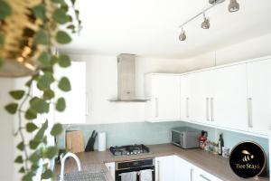 a kitchen with white cabinets and a stove top oven at Bee Stays - Ambleside House in Warrington