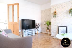 een woonkamer met een tv en een bank bij Bee Stays - Ambleside House in Warrington