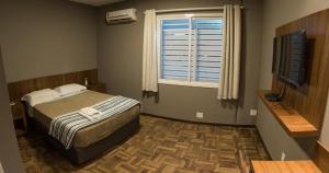 a bedroom with a bed and a window and a television at Ipê Hotel Express in Ponta Grossa